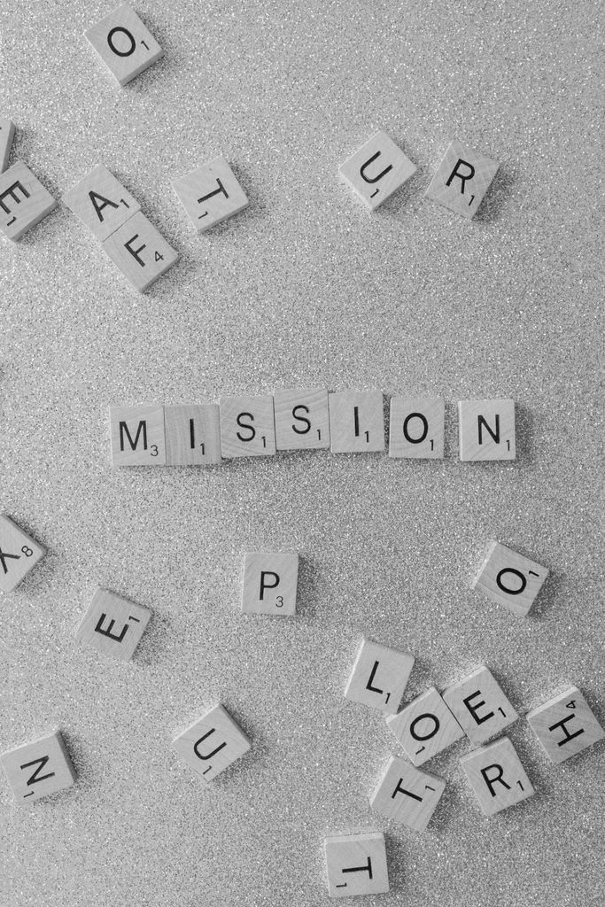 Scrabble tiles spelling 'MISSION' on a glittery surface, a symbolic and creative concept.